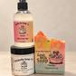 Paradise body and hair mist above a hand and body cream jar, beside a colorful goat milk soap bar.